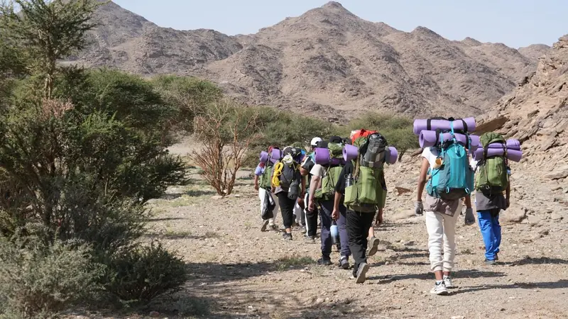 مجموعة تمشي بحقائب الظهر في وادٍ بين الجبال